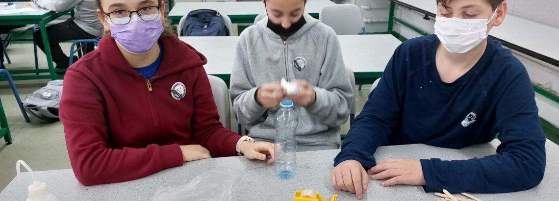 תלמידי מדעית ח’ מבצעים את אתגר ה”ביצה הצונחת” במהלך שיעור העשרה